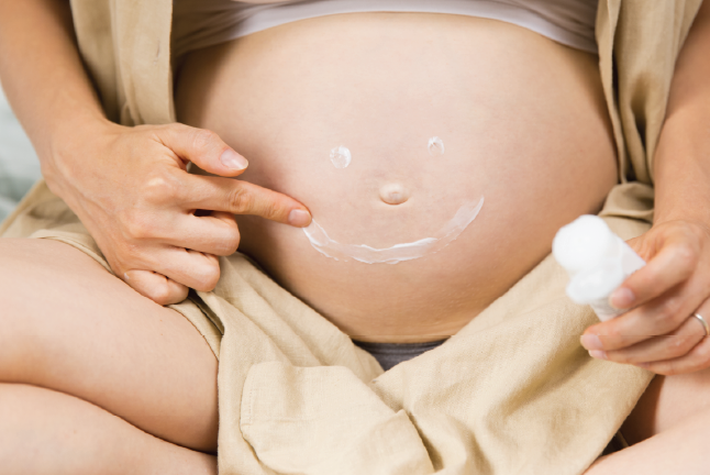 Pregnant woman applying lotion
